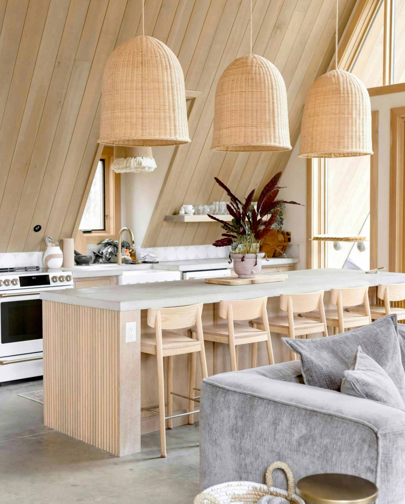 Modern short-term rental kitchen with rattan pendant lights, island seating, and premium guest-ready design.