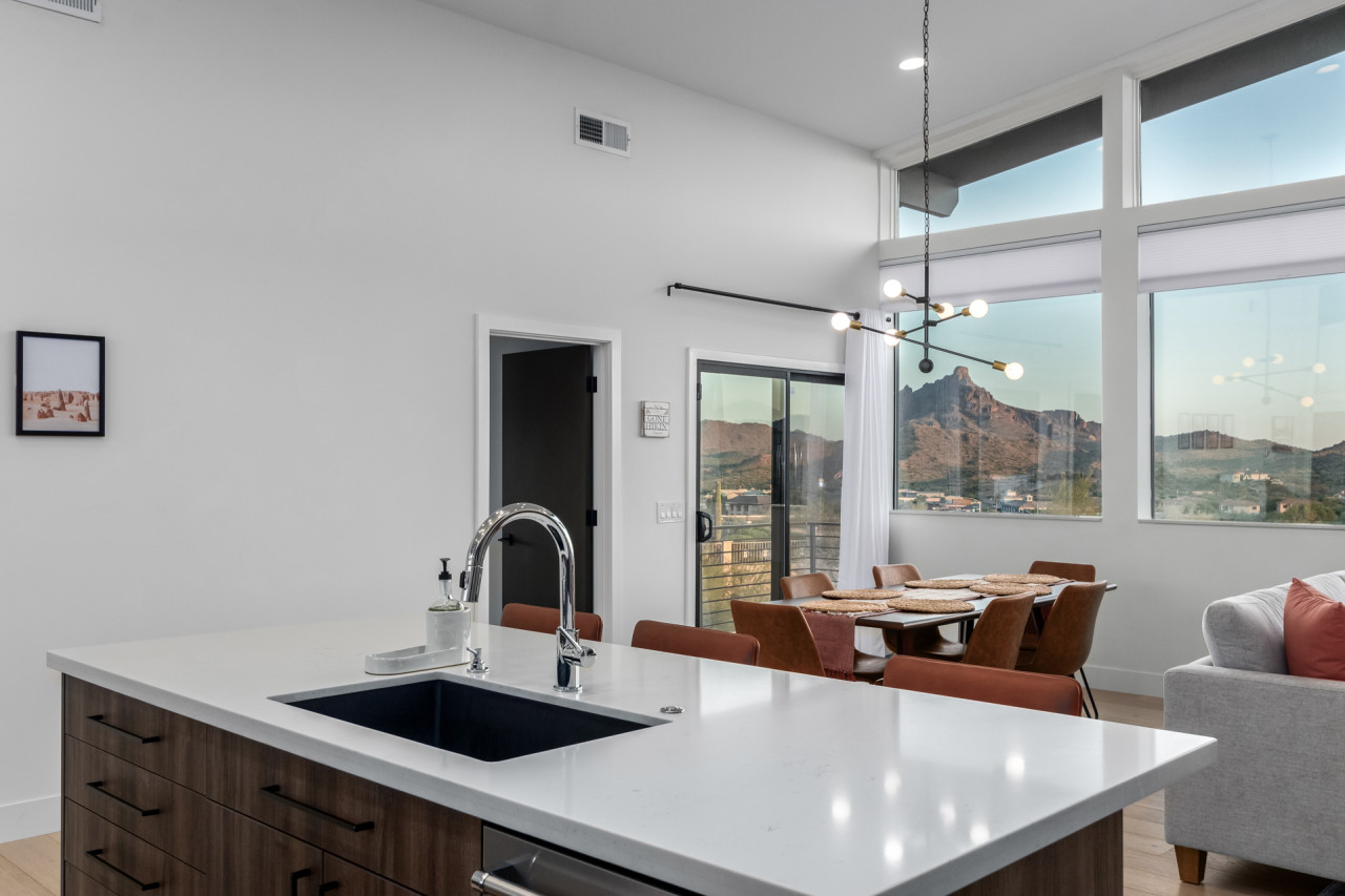 Luxury Scottsdale Airbnb interior featuring a modern kitchen island, floor-to-ceiling windows, and desert mountain views in a professionally designed short-term rental.