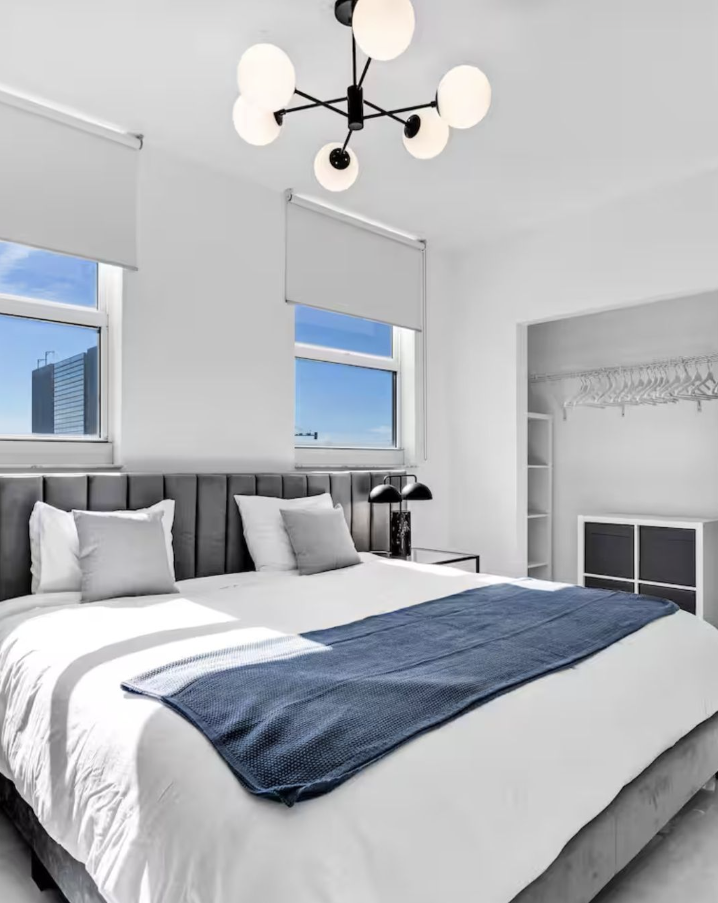 Modern white bedroom with upholstered bed, minimalist chandelier, and large windows in a luxury Scottsdale short-term rental interior.